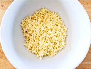 Skål med riven ost, placerad på en träyta.