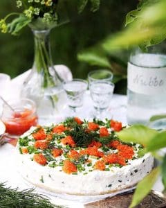 En midsommarcheesecake med gräslök och rom på toppen, placerad på ett bord.