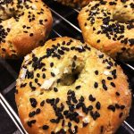 Tre bagels med svart sesamfrö och havssalt på en bakplåt.