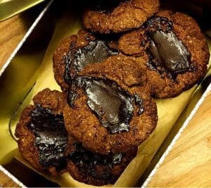 En låda med flera kakor som har en mörk chokladfyllning i mitten.