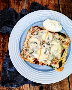 Taco-gummabröd med grönsaker, ost och en klick sås på en tallrik.