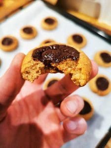En hand håller en bit av en chokladgrotta med en bit tagen ur den.
