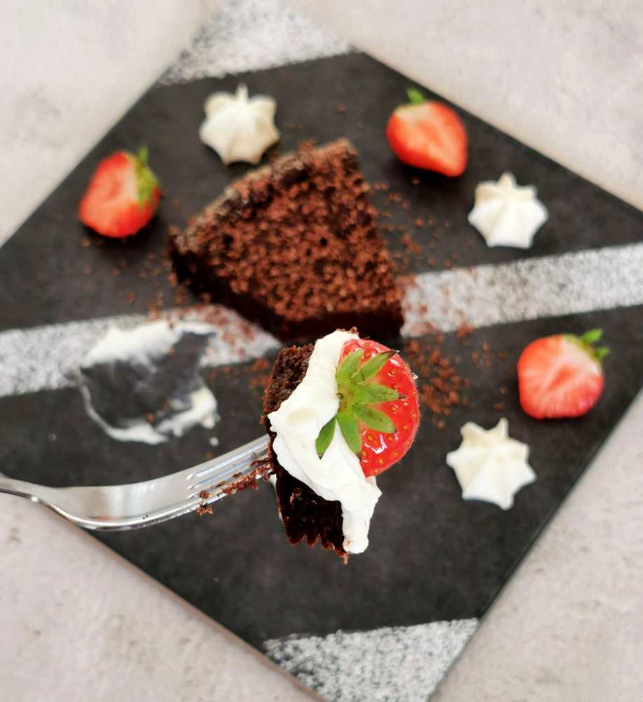 Kladdkaka - Magiskt god! 6 En gaffel med lite kladdkaka, en bit jordgubbe och lite grädde på