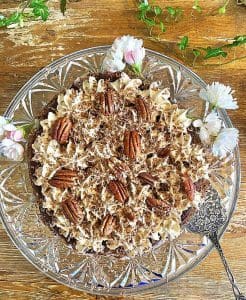 Kladdkaka toppad med grädde, chokladspån och pecannötter på en glasskål.