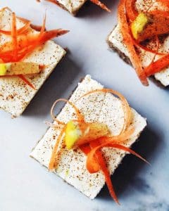 Morotskaka med vit glasyr, dekorerad med morotsstrimlor och en bit citron.