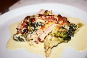 En tallrik med kassler och broccoligratäng täckt av sås.