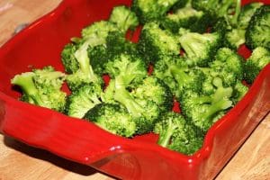 Röd ugnsform fylld med färsk broccoli i olika storlekar.