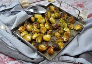 En plåt med ugnsstekta brysselkål som är gyllenbruna och krispiga.