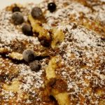 Amerikanska pannkakor toppade med florsocker och blåbär på en tallrik.