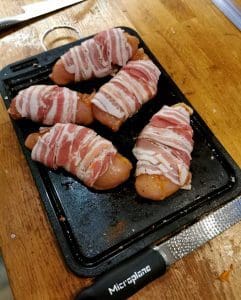 Fyra baconlindade kycklingfiléer placerade på en svart plåt.