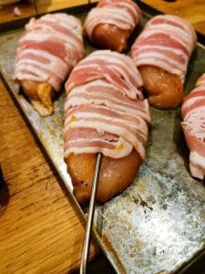 Baconlindade kycklingfiléer placerade på en plåt med en metallspett.
