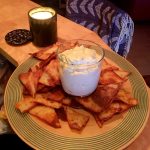 En tallrik med friterade tortillachips och en skål med dipp i mitten.