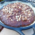 Grillad kladdkaka med mandel på toppen i en svart stekpanna.