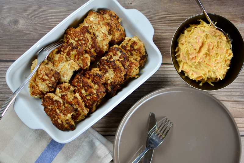 Kycklingfärsbiffar med fetaost 5 Kycklingfärsbiffar på en rund tallrik sedda uppifrån med en skål coleslaw bredvid.