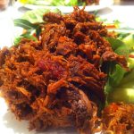 En portion pulled beef serverad med grönsaker på en tallrik.