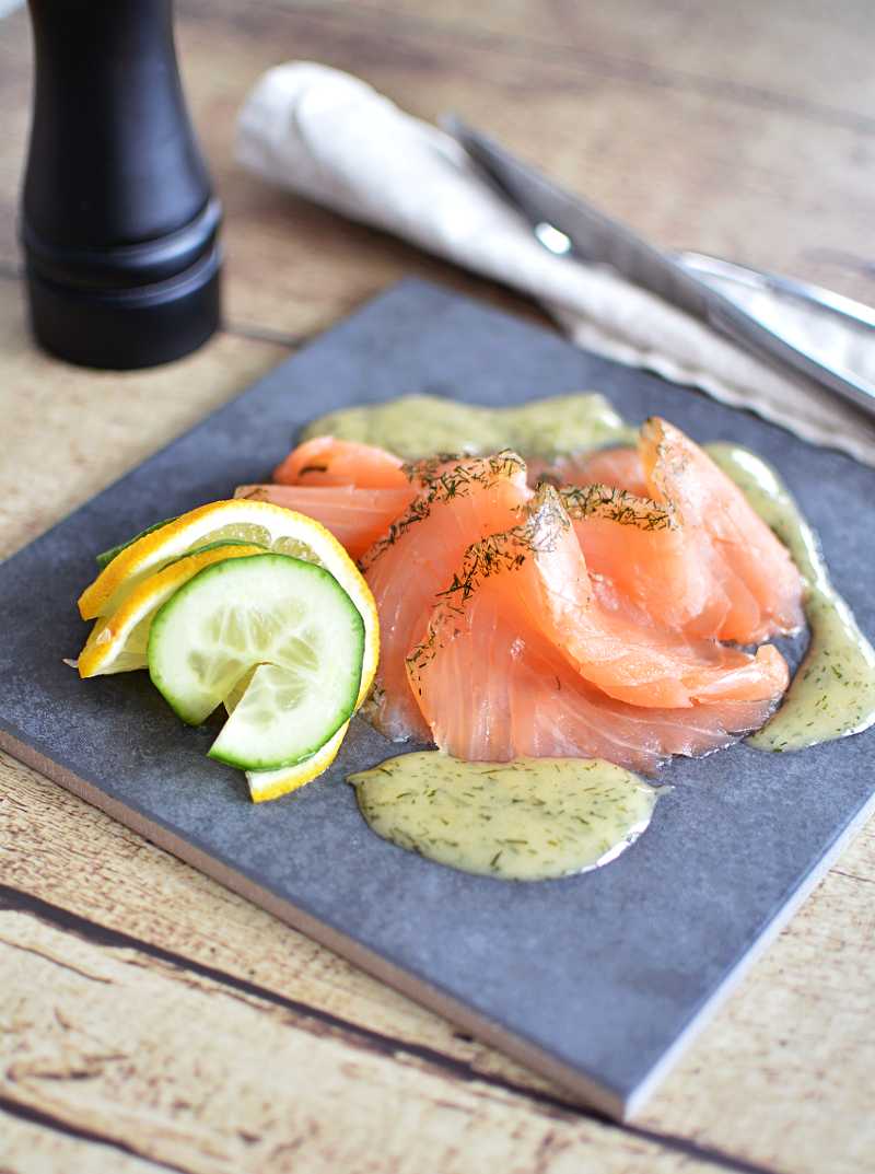 Hovmästarsås 6 Skivad gravlax på en grå tallrik med hovmästarsås runt.