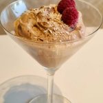 Chokladmousse i ett martiniglas, dekorerad med hallon och kokosflingor.