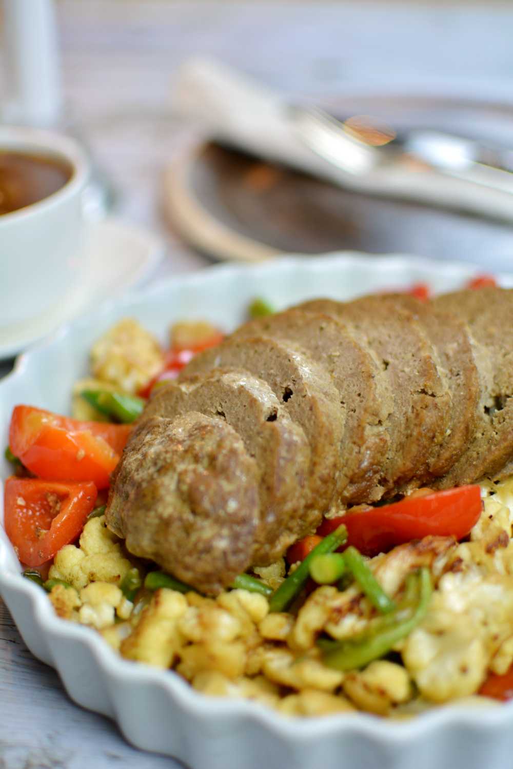 Köttfärslimpa 6 Närbild på en uppskivad köttfärslimpa på en bädd av grönsaker.