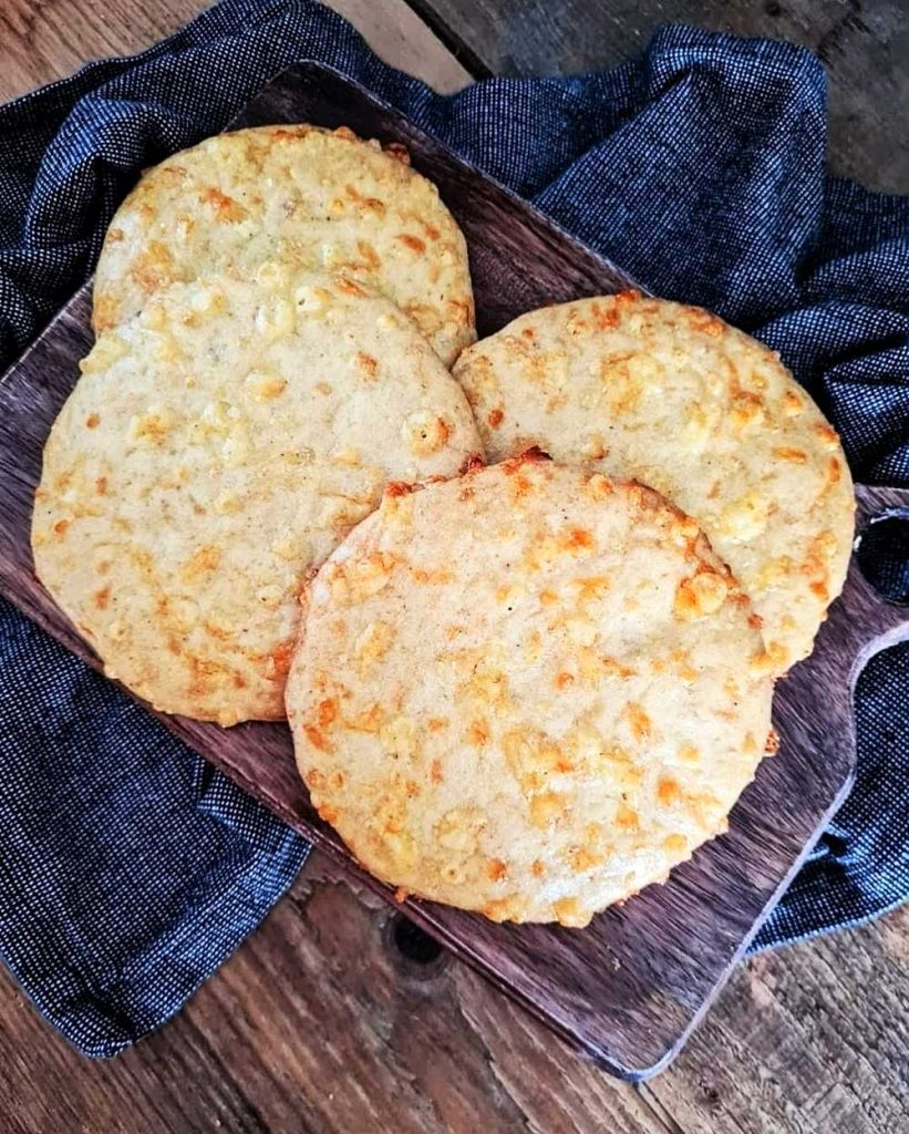 Kesobröd med solroskärnor 7 Fyra ostbröd placerade på en träskärbräda med en mörk duk i bakgrunden.