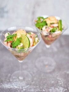 Två martiniglas med räksallad, limeklyfta och koriander på toppen.