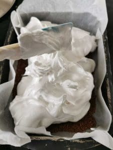 En bakform med vispad grädde som täcker ett lager av chokladmassa.