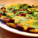 En svampomelett med Västerbottensost och ruccola på en vit tallrik.