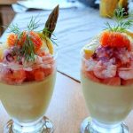 Två glas med sparris pannacotta toppade med räkor, lax och dill.