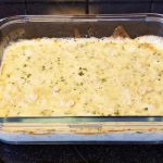 Ugnsform med parmesangratinerade räkor täckta av ett gyllene lager ost.