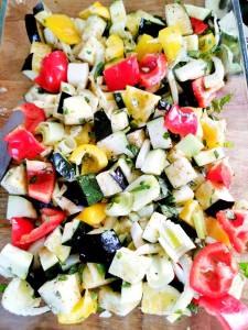 En ugnsform fylld med tärnade grönsaker som zucchini, paprika och purjolök.