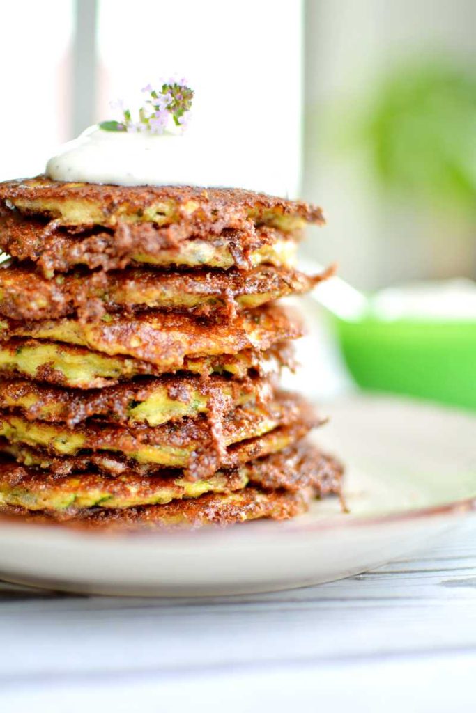 Parmesan och vitlöksbakad zucchini 12 En hög av zucchinifritters med en klick gräddfil och en ört på toppen.