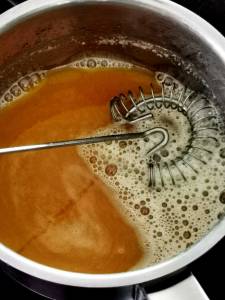 Kastrull med smält smör och en metallvisp som rör om i innehållet.