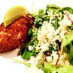 Grillad kycklingfilé med en skiva lime och en sallad av gröna blad och riven blomkål.