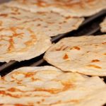 Flera nygräddade tortillas som ligger på ett galler för att svalna.