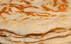 Staplade tortillas med en gyllenbrun yta, fotograferade på en mörk bakgrund.