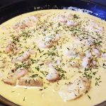 En panna med torsk och räkor i en vitvinssås, toppad med dill.