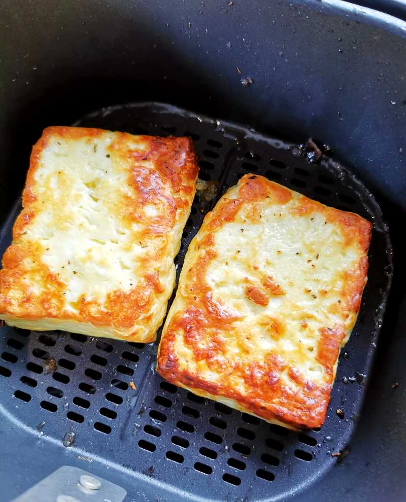 Airfryer - Helstekt kotlettrad 11 Två bitar grillad halloumi i en airfryer med gyllenbrun yta.
