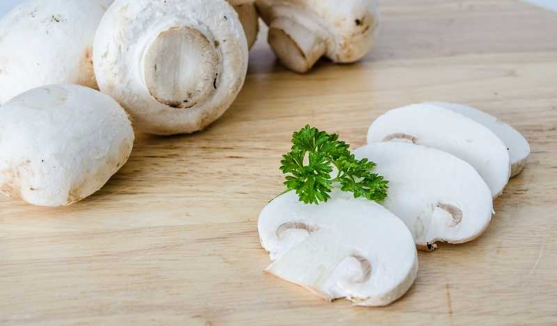 Marinerade champinjoner 4 Skivade champinjoner på en träskiva.