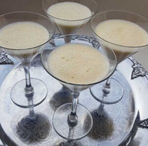 Fyra glas med pannacotta på en silverbricka, dekorerade med limemarinerade bär.