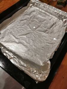 En bakplåt täckt med aluminiumfolie som ligger på en bänk.