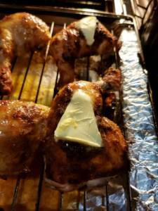 Grillade kycklingklubbor i ugn med en bit smör på toppen.