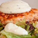 Laxburgare med limeaioli placerad på en bädd av grönsallad.