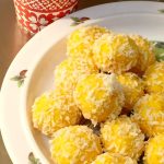En tallrik med saffransbollar täckta av kokosflingor, placerade på en vit tallrik.