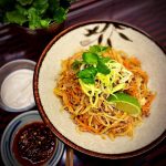 En skål med asiatisk nudelrätt som innehåller köttfärs, grönsaker och lime.
