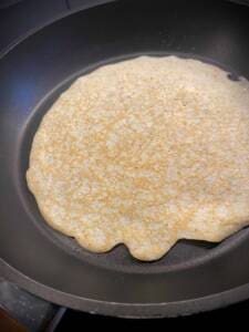 En tortilla som grillas i en stekpanna, med en jämn och ljus yta.