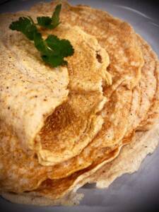 Tre tortillas staplade på en tallrik med en kvist koriander ovanpå.