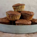 En hög av chokladmuffins i en grön tallrik med en neutral bakgrund.
