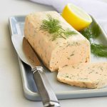 En skiva laxpaté med dill och citron på en tallrik med en kniv bredvid.