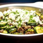 En panna med köttfärs, zucchinis, pesto och färskost på toppen.