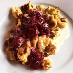 En tallrik med scrambled pancakes toppade med hallon och grädde.