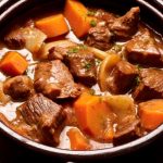Karelsk stek med köttbitar och grönsaker i en svart gryta.
